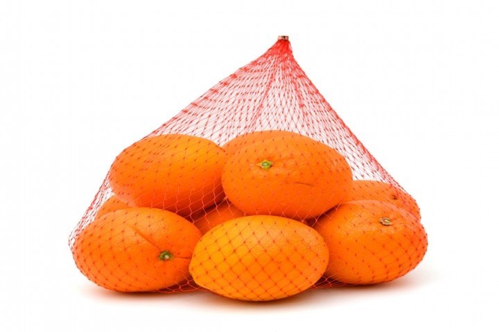 packaging products fresh oranges in plastic mesh sack on white background